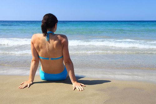 Žena sedí na pláži