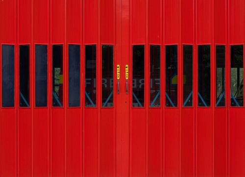 Červené dveře s hasiči vzadu