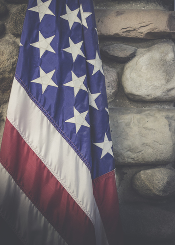 US flag in front of stone wall