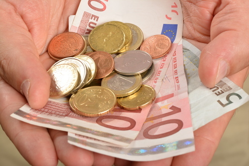 Notas de euro e as moedas em uma mão