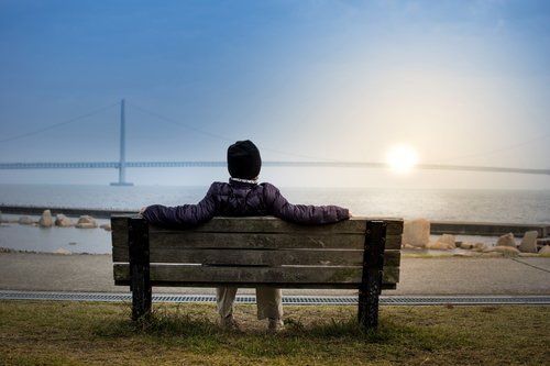 Mannen sitter på en bänk som solnedgången