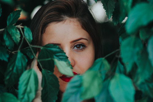 Jeune fille derrière les feuilles