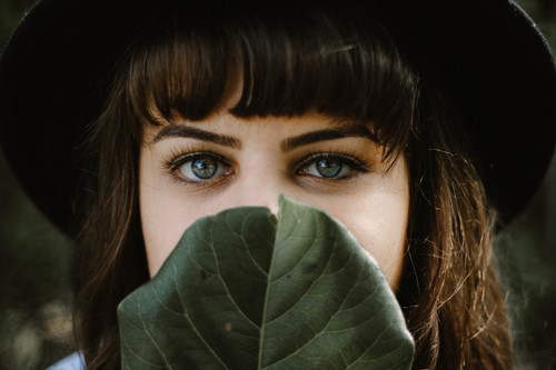 Woman covering her lips with leaf