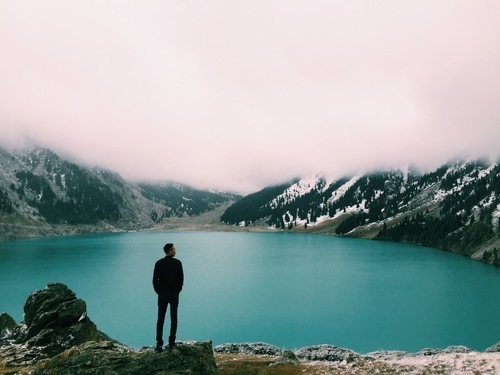 Hombre de pie junto al lago azul