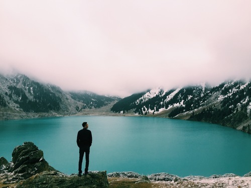 Uomo in piedi dal lago blu