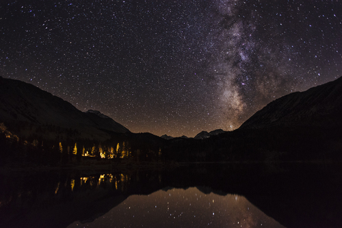 Starry night sky over mountains and water