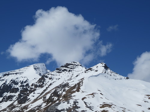 Snötäckta bergstopp under stora moln