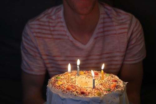 Cake with lit candles and person behind