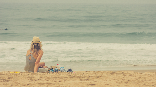 Flickan sitter på stranden