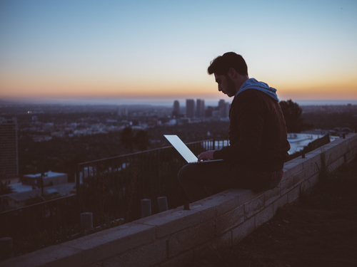 Homem sentado no terraço com laptop