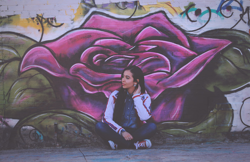 Menina que senta-se no fornt dos grafittis