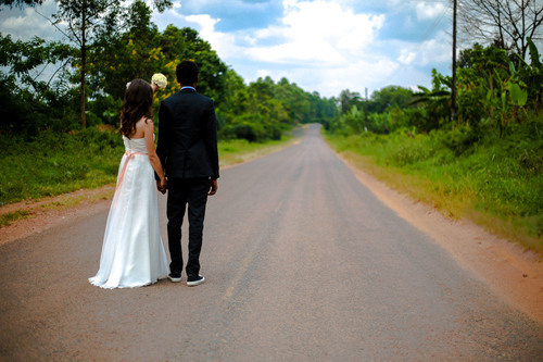 Невеста в белом платье бежит по дороге