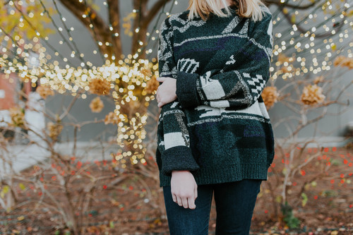Girl in sweater with decorative lights behind