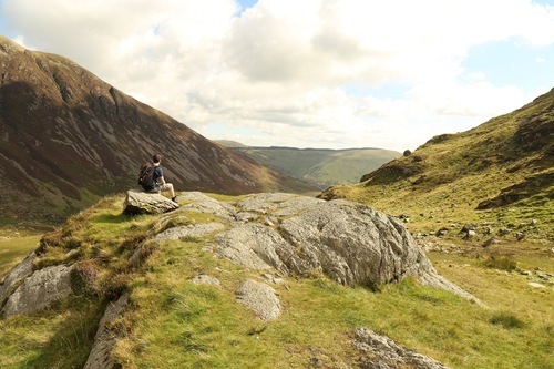 Uomo che si siede su una roccia in natura