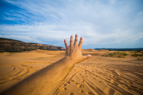 Male hand spread towards sand