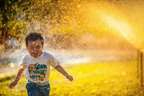 Kind loopt door de sprinklers