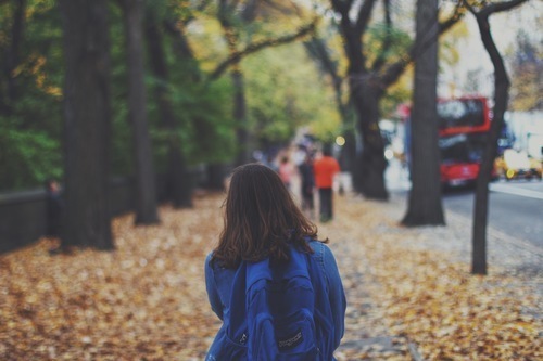 Menina de atrás na rua frondosa