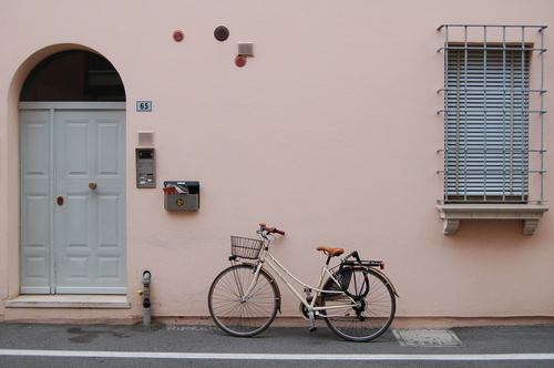 Bicicleta retro apoyada en fachada rosa