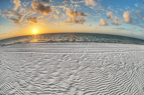 Pôr do sol e a praia de areia listrada