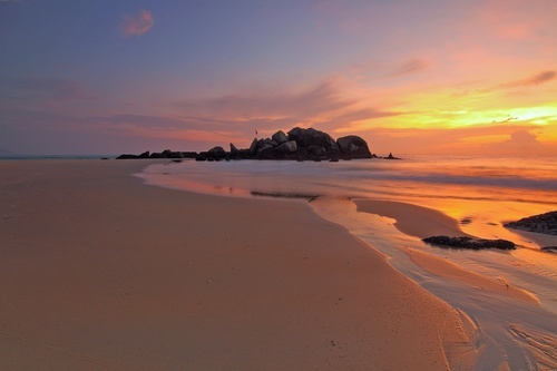 Lunga spiaggia di sabbia con il tramonto colorato