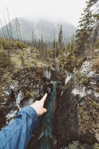 Main, pointant vers une rivière