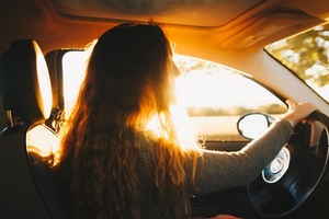 Long-haired woman behind the car wheel